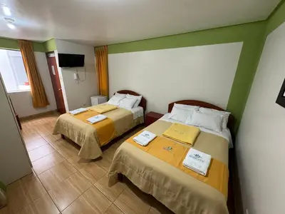a hotel room with two beds and a television at Illari Wari l - Hotel Sauna in Ayacucho