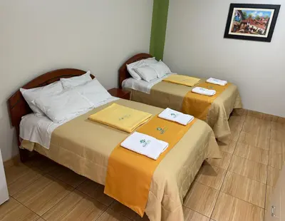 two beds in a hotel room with towels on them at Illari Wari l - Hotel Sauna in Ayacucho