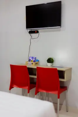 a desk with two chairs and a television on a wall at Hotel Venture in Chincha Alta