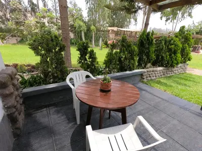 a wooden table and white chairs on a patio at Villas de Cieneguilla in Cieneguilla