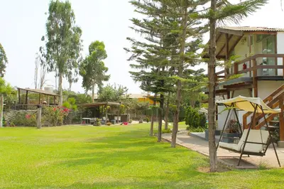 a yard with trees and a house with a swing at Villas de Cieneguilla in Cieneguilla