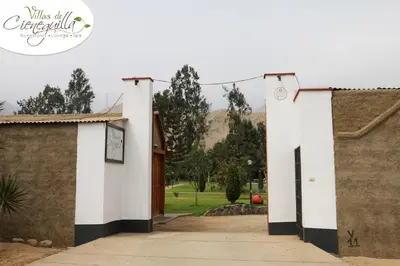 a white building with black and white columns at Villas de Cieneguilla in Cieneguilla