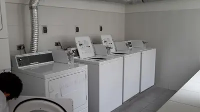 a white laundry room with three machines and a washer at Lima Flats 3 in Lima