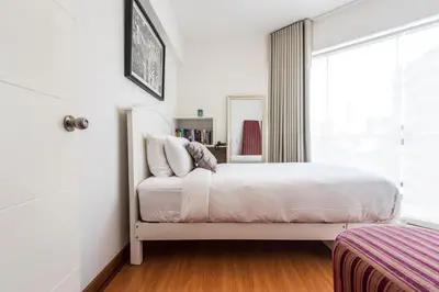 a white bedroom with a bed and a window at InkaHuset Miraflores Deluxe in Lima