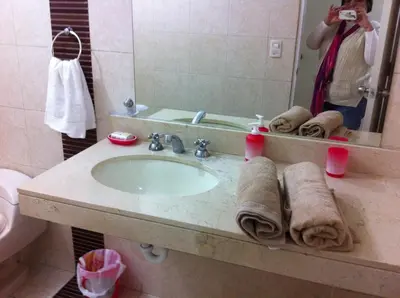 a woman taking a picture of a bathroom sink at Departamento Miraflores in Lima