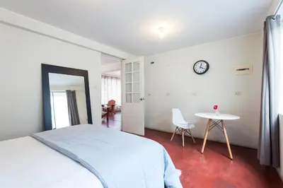 a bedroom with a bed and a table and a clock at InkaHuset Airport in Lima