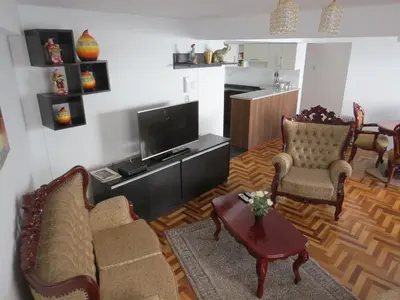 a living room with a couch and chairs and a tv at Apartamentos Quewe in Cusco