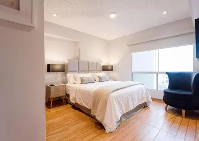 a bedroom with a bed and a blue chair at OceanFront Larcomar Apartments in Lima