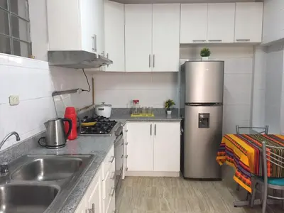 a kitchen with white cabinets and a stainless steel refrigerator at Kelebek Hostel in Lima