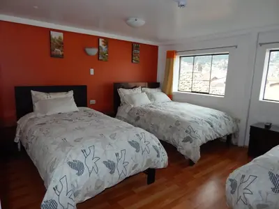two beds in a room with orange walls at Hospedaje Qori Punku in Cusco