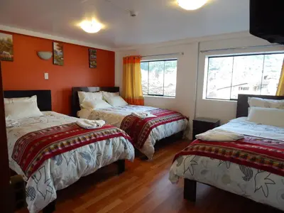 two beds in a room with orange walls at Hospedaje Qori Punku in Cusco
