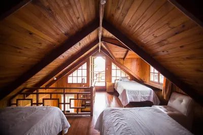 a room with two beds in a wooden attic at Cemayu Lodge in Oxapampa