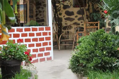 a patio with a brick wall and chairs and flowers at Killari B&B in Ollantaytambo
