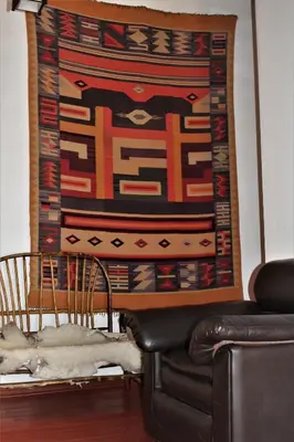 a large rug hanging on a wall next to a couch at Killari B&B in Ollantaytambo