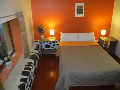 a bedroom with a large bed and orange walls at Killari B&B in Ollantaytambo