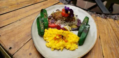 a plate of food with vegetables on a wooden table at Hommam in Cusco