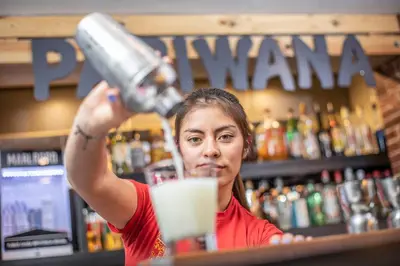 a woman is making a drink at a bar at Pariwana Hostel Lima in Lima