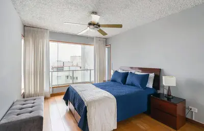 a bedroom with a blue bed and a ceiling fan at Oceanfront Miraflores Larcomar next to Marriott in Lima