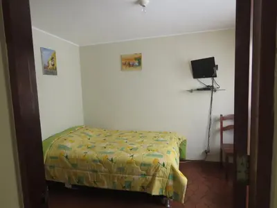 a bedroom with a bed and a tv on the wall at Casa particular de Jorge Edinson in Lima