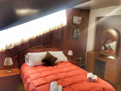 a bedroom with a bed with red comforter and a mirror at Del Niño Apartment, Best location in Cusco