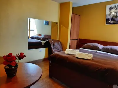 a room with two beds and a table and a mirror at Hostal Don Cristobal in Ayacucho