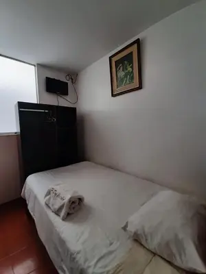 a bedroom with a white bed with a picture on the wall at Hostal Don Cristobal in Ayacucho
