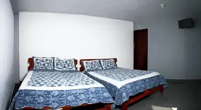 a bedroom with two beds with blue and white sheets at Hostal Los Angeles in Barranca