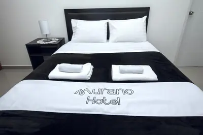 a bed with a black and white blanket and towels on it at Hotel Murano in Abancay