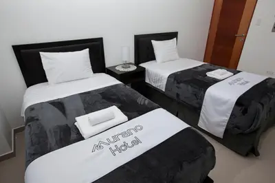 two beds with black and white sheets in a room at Hotel Murano in Abancay