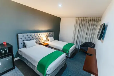 a hotel room with two beds and a television at Hotel Hacienda Lima Norte in Lima