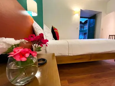 a bedroom with a bed and a vase with flowers on a table at Usgar San Pedro Boutique in Cusco
