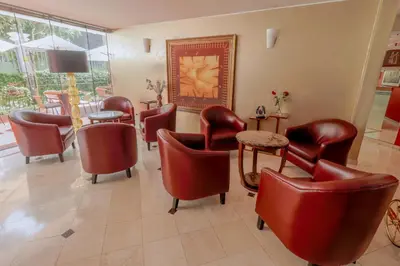 a waiting room with red chairs and a table at Hotel Boutique Runcu Miraflores in Lima