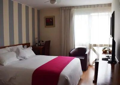 a hotel room with a bed and a chair and a window at Hotel Boutique Runcu Miraflores in Lima