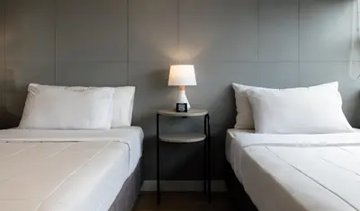 two beds in a room with a lamp on a table at Miraflores Suites Centro in Lima