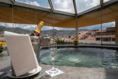 a bottle of champagne and a wine glass next to a swimming pool at Hotel Jose Antonio Cusco in Cusco