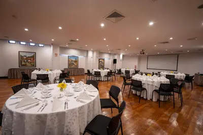 a banquet hall with white tables and chairs and a screen at Hotel Jose Antonio Cusco in Cusco