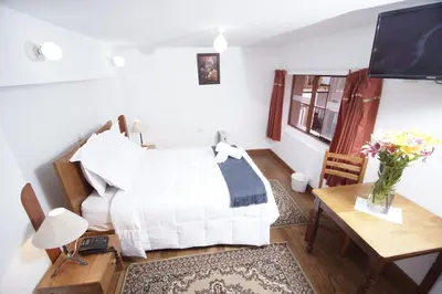a bedroom with a bed and a table and a television at Casa Union Cusco in Cusco
