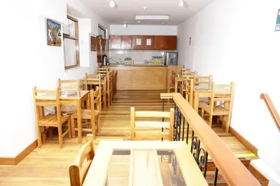 a restaurant with wooden tables and chairs and a kitchen at Casa Union Cusco in Cusco