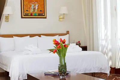 a bedroom with a bed with a vase of flowers on a table at La Hacienda Bahia Paracas in Paracas