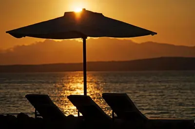 a beach with chairs and an umbrella in front of the ocean at La Hacienda Bahia Paracas in Paracas