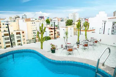 a pool on the roof of a building with tables and chairs at Embajadores Hotel in Lima
