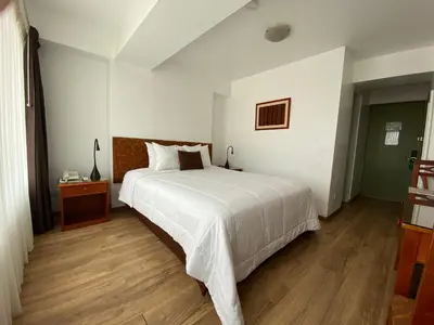 a bedroom with a white bed and a wooden floor at Faraona Grand Hotel in Lima