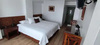 a bedroom with a white bed and a table and a television at Faraona Grand Hotel in Lima