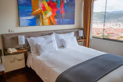 a bedroom with a white bed with a large window at Hotel Encantada Casa Boutique Spa in Cusco