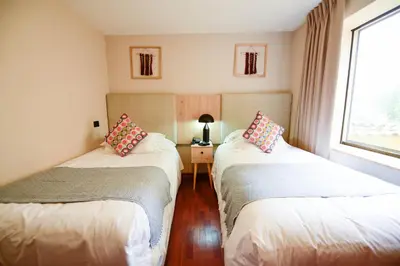two beds in a small room with a window at Torre Dorada Cusco in Cusco