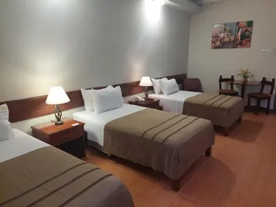 a hotel room with three beds and two lamps at Lima Wasi Hotel Miraflores in Lima