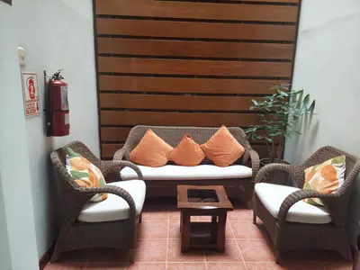 a living room with wicker chairs and a couch with pillows at Lima Wasi Hotel Miraflores in Lima