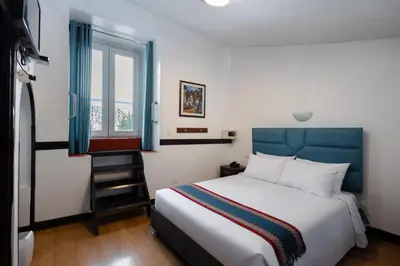 a bedroom with a bed with a blue headboard and a window at Hotel Hacienda Cusco Plaza in Cusco