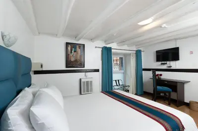 a bedroom with a white bed and a desk at Hotel Hacienda Cusco Plaza in Cusco