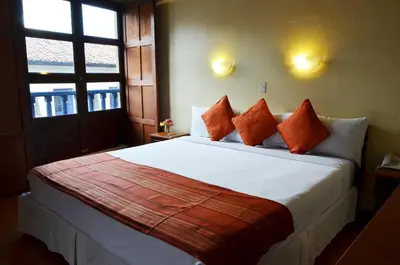 a bedroom with a large white bed with orange pillows at Nodo Cusco Santa Teresa in Cusco